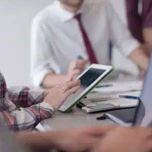 Team reviews analytics on tablet during meeting, planning upgrades; IT services for small business success