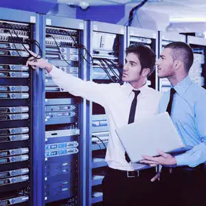 Engineers manage cabling in a server room, showing teamwork in comprehensive IT support services