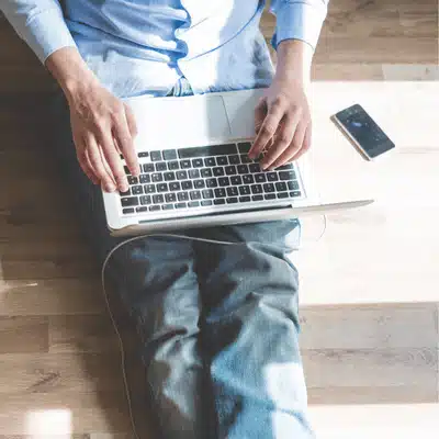 Person works on laptop with phone nearby managing systems for lenovo server solutions from home