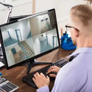 Security professional viewing multi-camera surveillance feed on desktop monitor as part of routine cctv maintenance operations