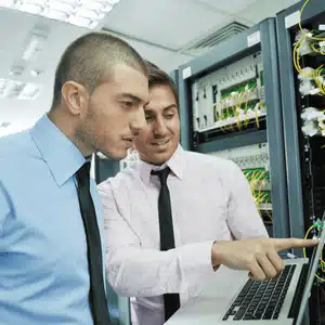 Two IT experts troubleshoot a network rack, delivering strategic and comprehensive IT support solutions