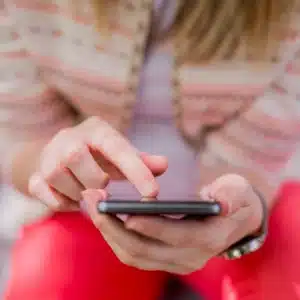 Woman uses smartphone app to check security camera feed, adjusting notifications and privacy settings remotely