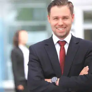 Professional security manager in suit smiles confidently outside building, representing reliable protection and client trust