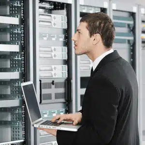 Technician uses a laptop to check server systems, ensuring comprehensive IT support efficiency