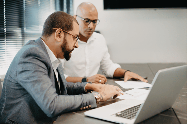 Two professionals review documents beside laptop, planning budgets and solutions with managed it services support