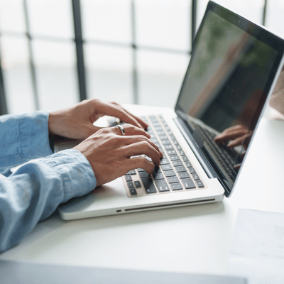 Hands type on laptop at desk, handling tickets and updates through managed it services today