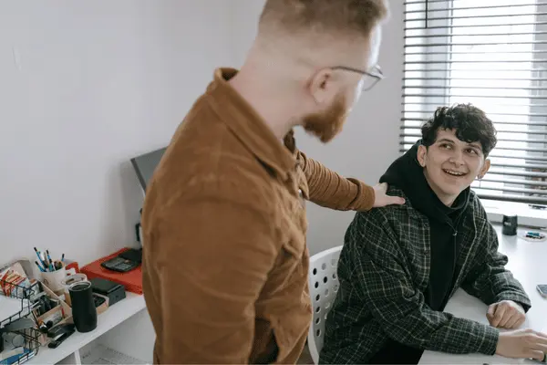 Coworker assists teammate at desk, solving issue quickly with Remote IT support for smooth work