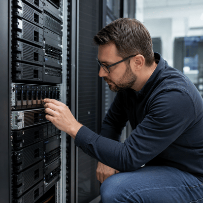 An IT technician closely inspects a rack-mounted server component while assessing hardware used by the best server brands